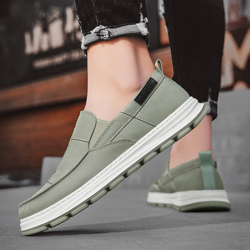 Green slip-on shoes with white soles worn by a person on a blurred background