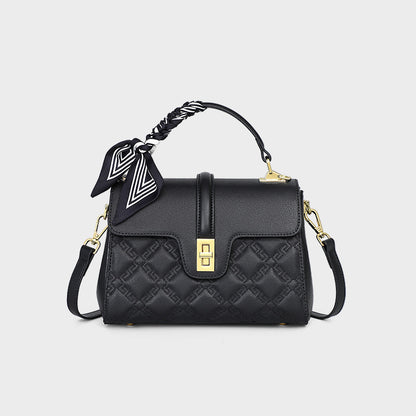Black quilted handbag with gold accents on a light gray background