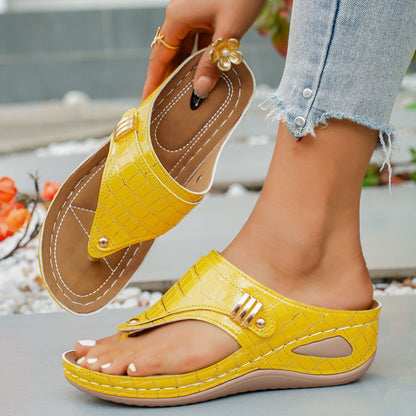 Yellow sandals with brown soles worn by a person, with a blurred outdoor background.