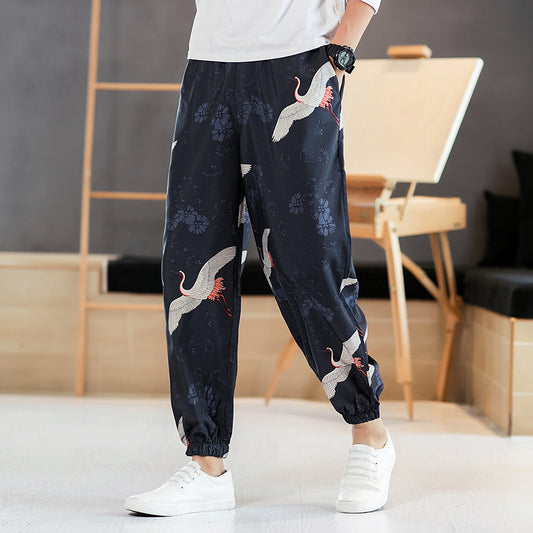 Person wearing navy blue pants with bird embroidery in a room setting