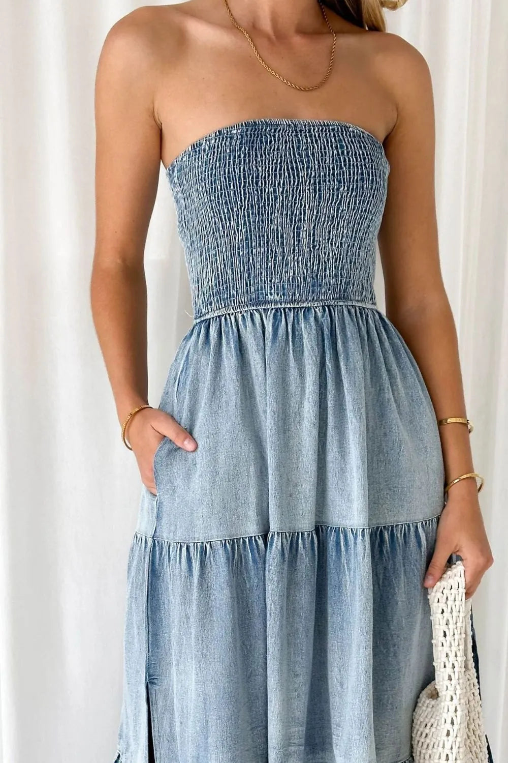 Woman wearing a strapless denim dress against a white background