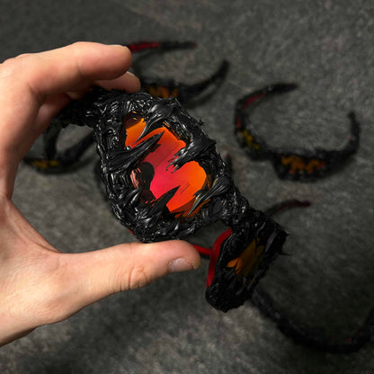 Hand holding a black and orange dragon-shaped object on a dark surface