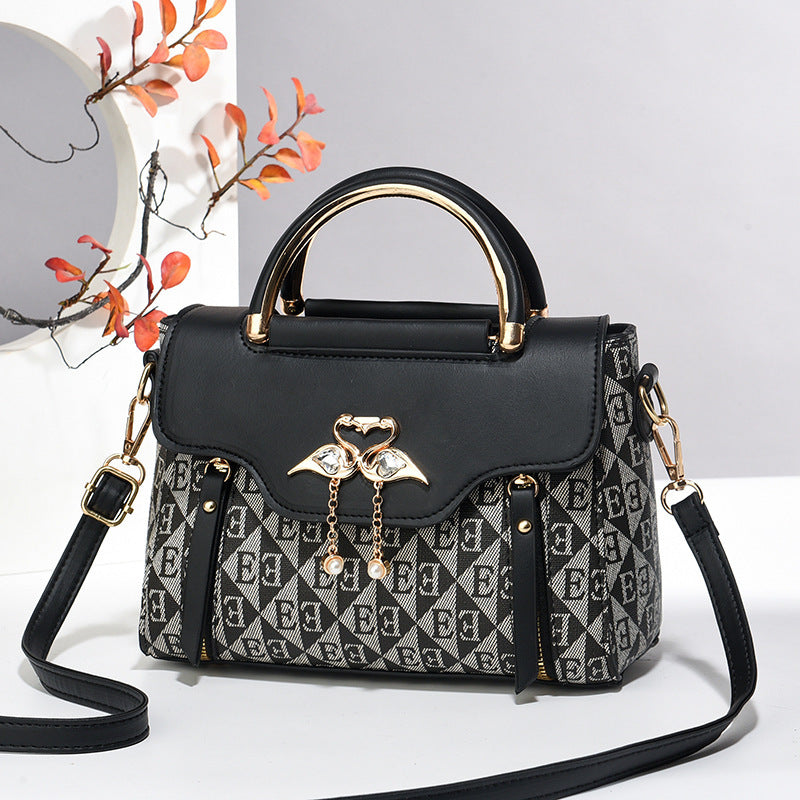 Black handbag with patterned flap and decorative chain on a white background