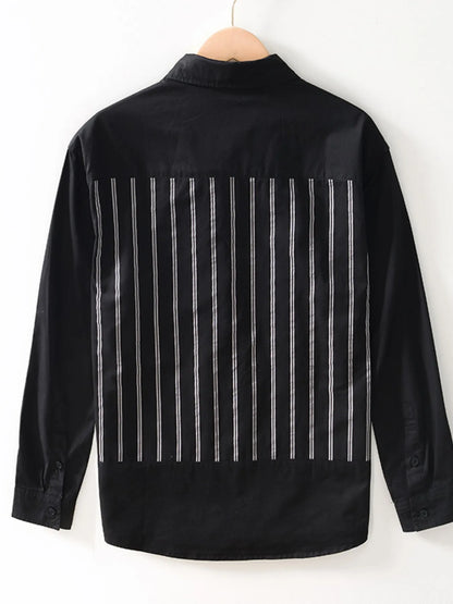 Black shirt with white vertical stripes on a hanger against a white background