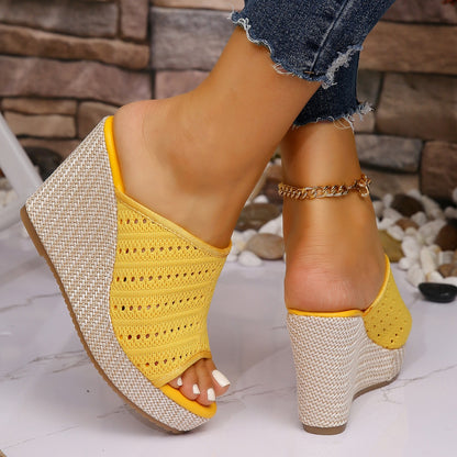 Yellow wedge sandals with woven design on a stone and pebble background