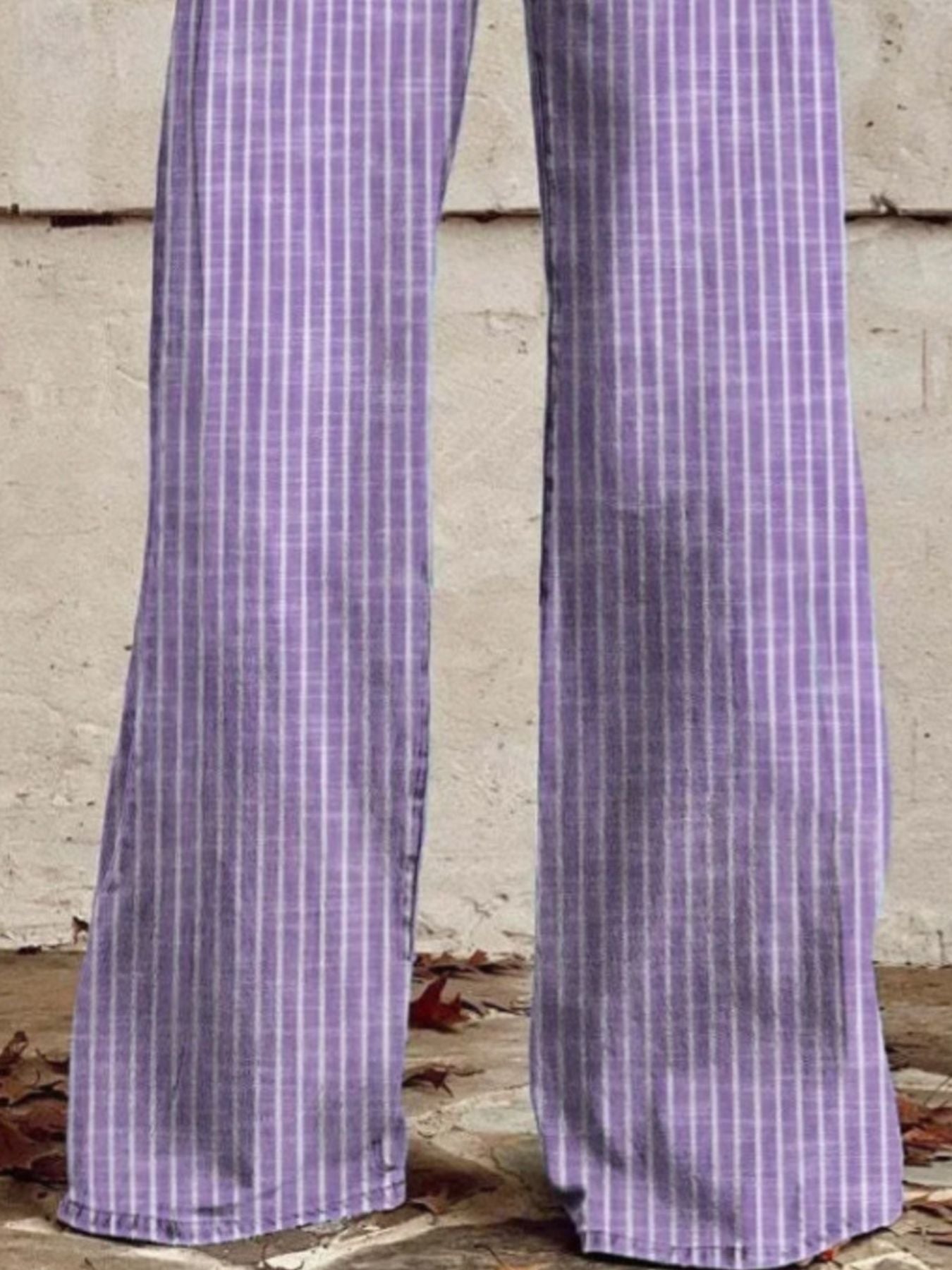 Purple checkered pants worn by a person against a concrete wall.