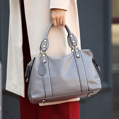 Person holding a gray handbag with a blurred background