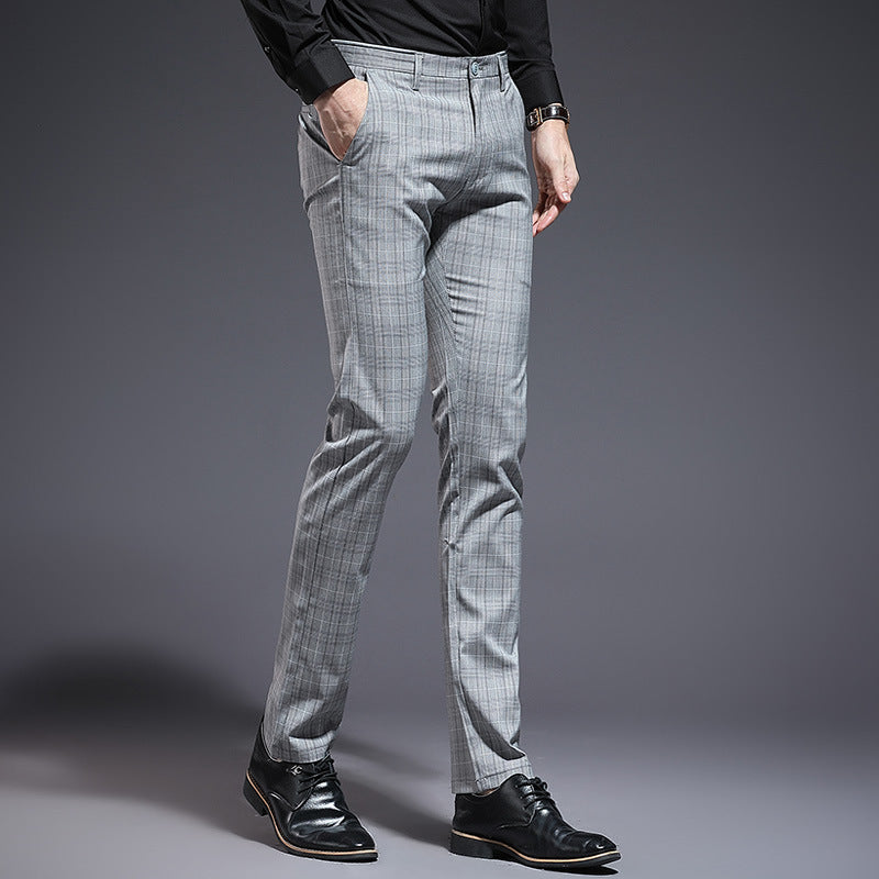 Person wearing gray checkered pants and black shoes on a gray background