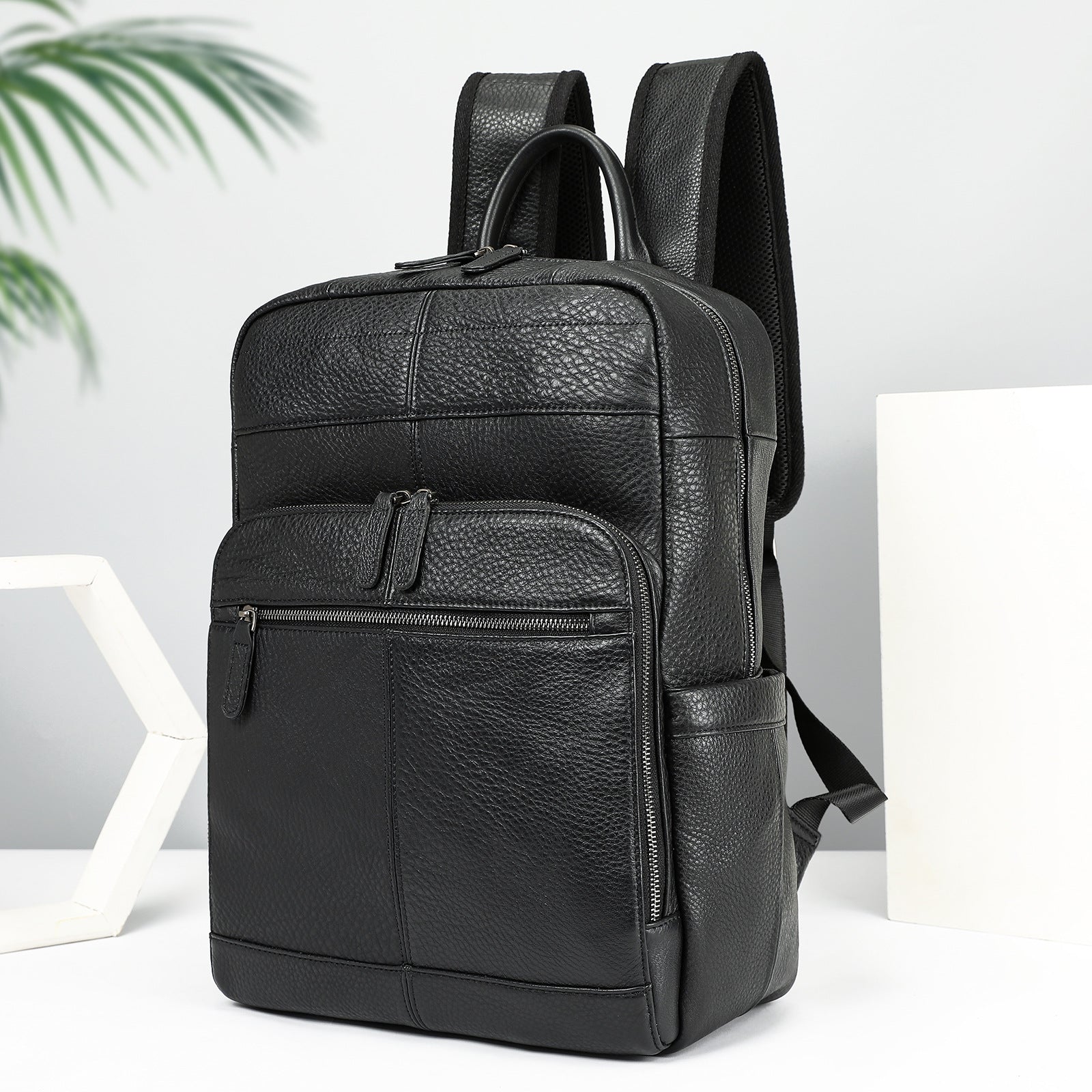 Black leather backpack on a white surface with a light gray background