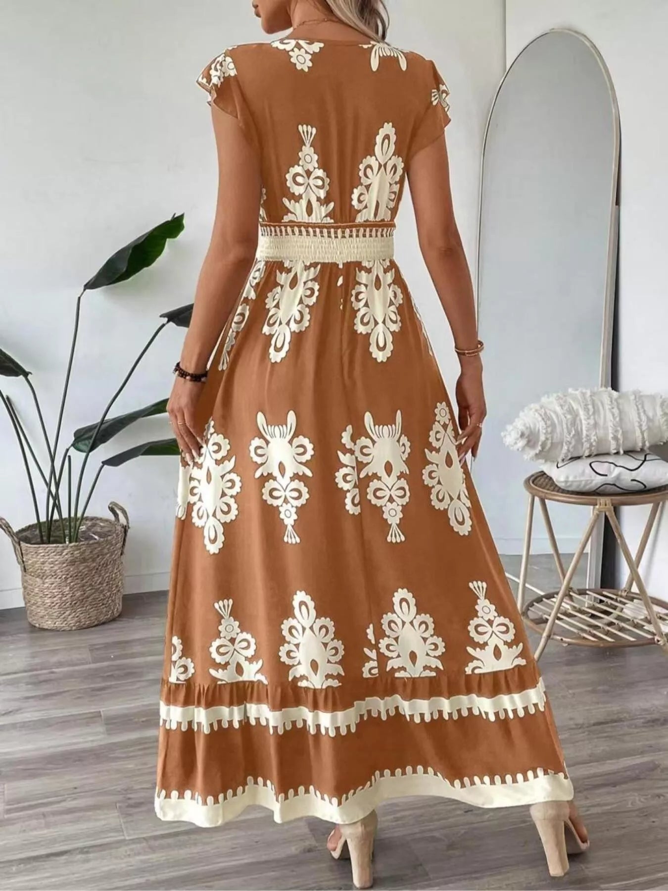 Woman wearing a brown dress with white lace patterns in a room.