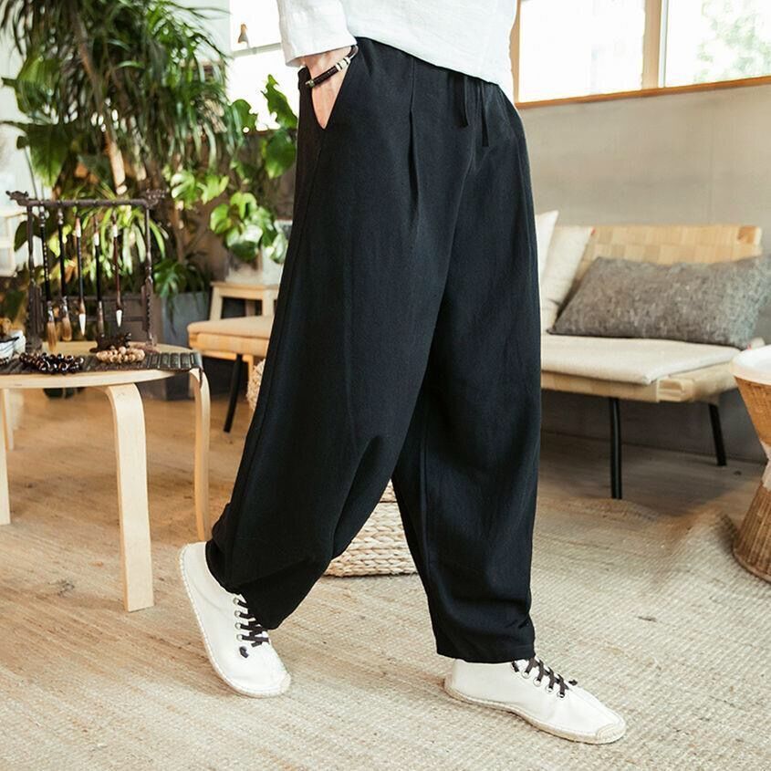 Person wearing black wide-leg pants and white sneakers in a living room setting.