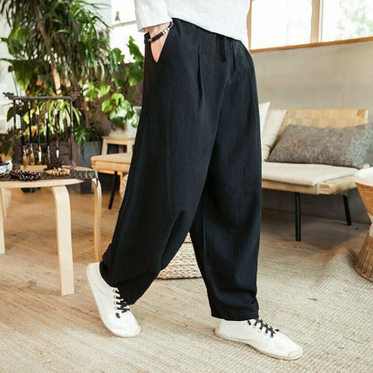 Person wearing black wide-leg pants and white sneakers in a living room setting.
