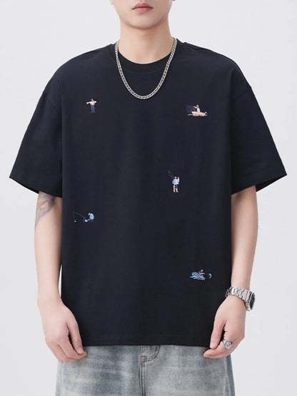 Person wearing a black t-shirt with small embroidered designs on a plain background