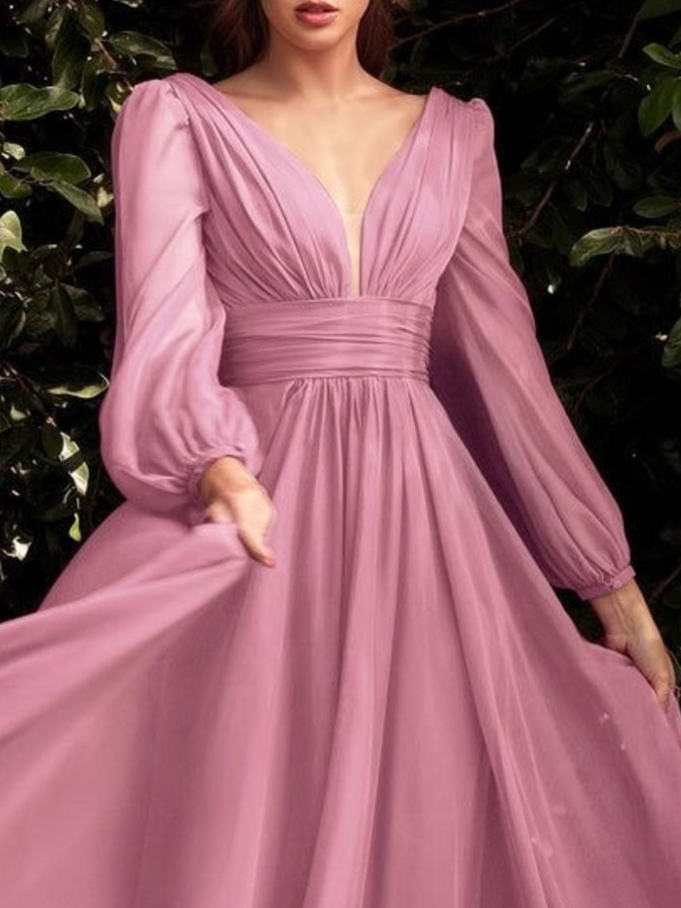 Pink evening gown with long sleeves against a dark background
