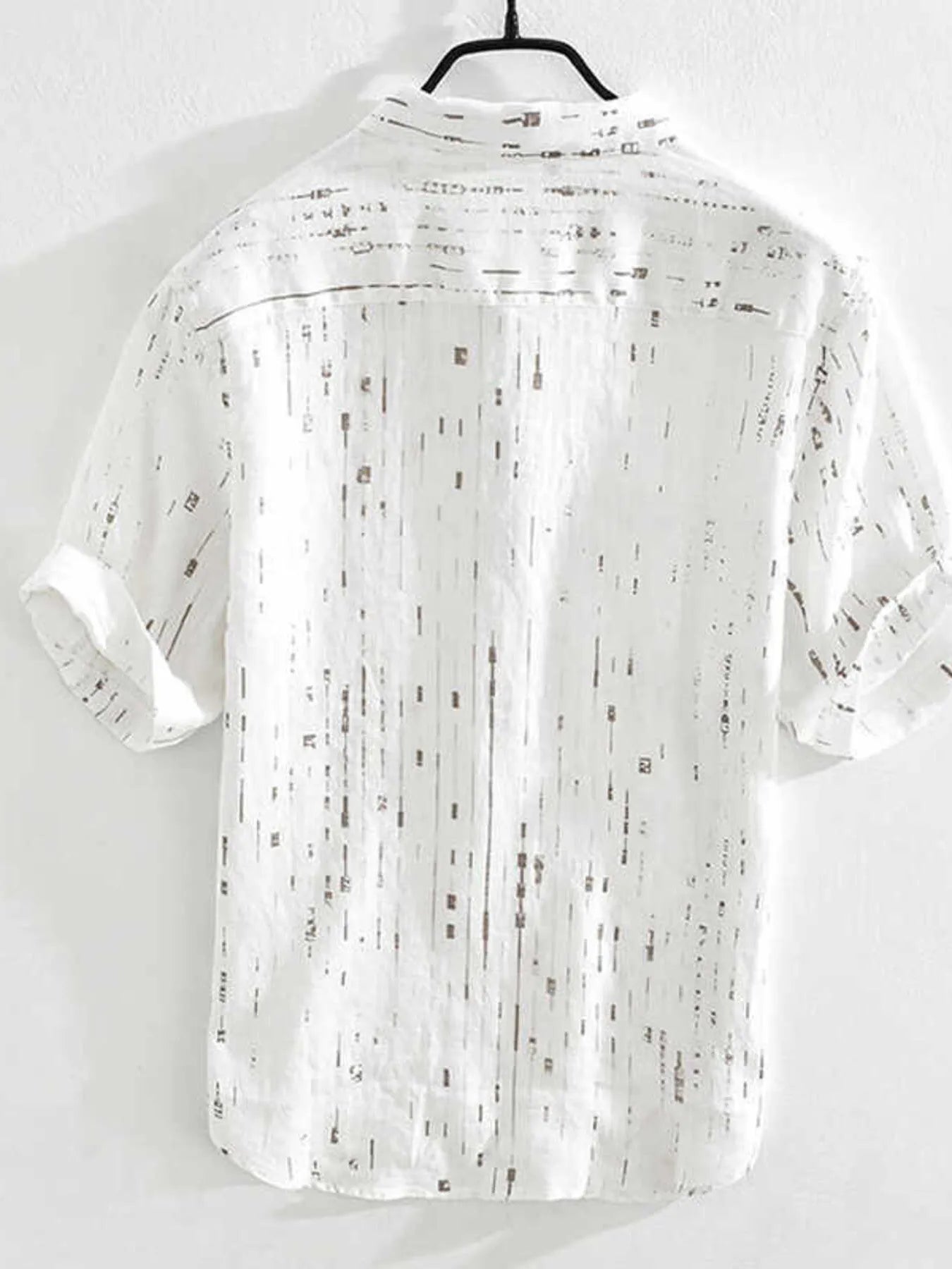 White shirt with black pattern on a hanger against a white background