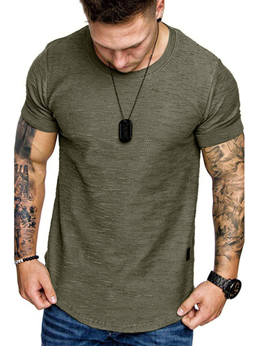 Man wearing an olive green t-shirt with tattoos on arms and a necklace.