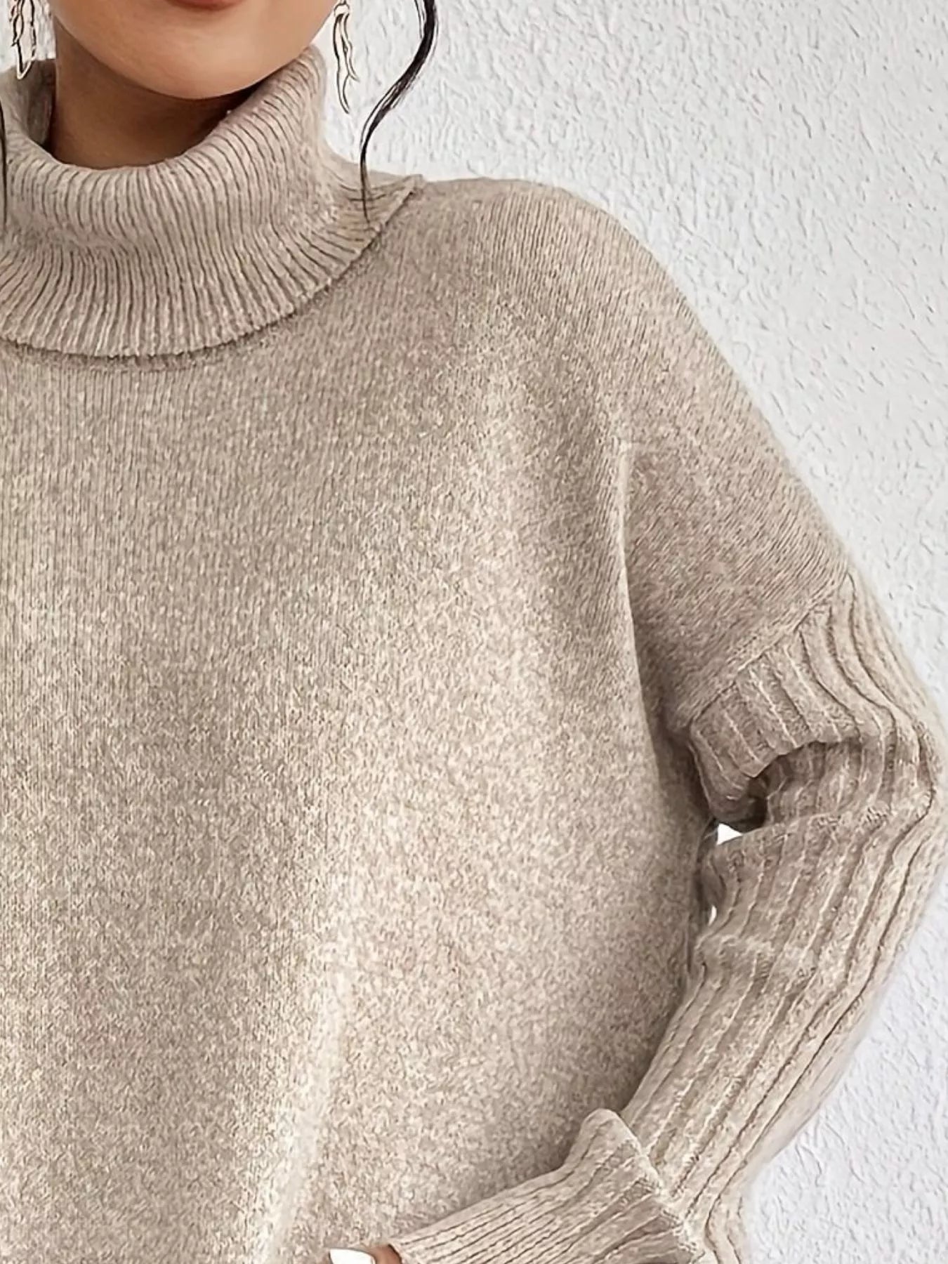 Beige turtleneck sweater worn by a person against a white background