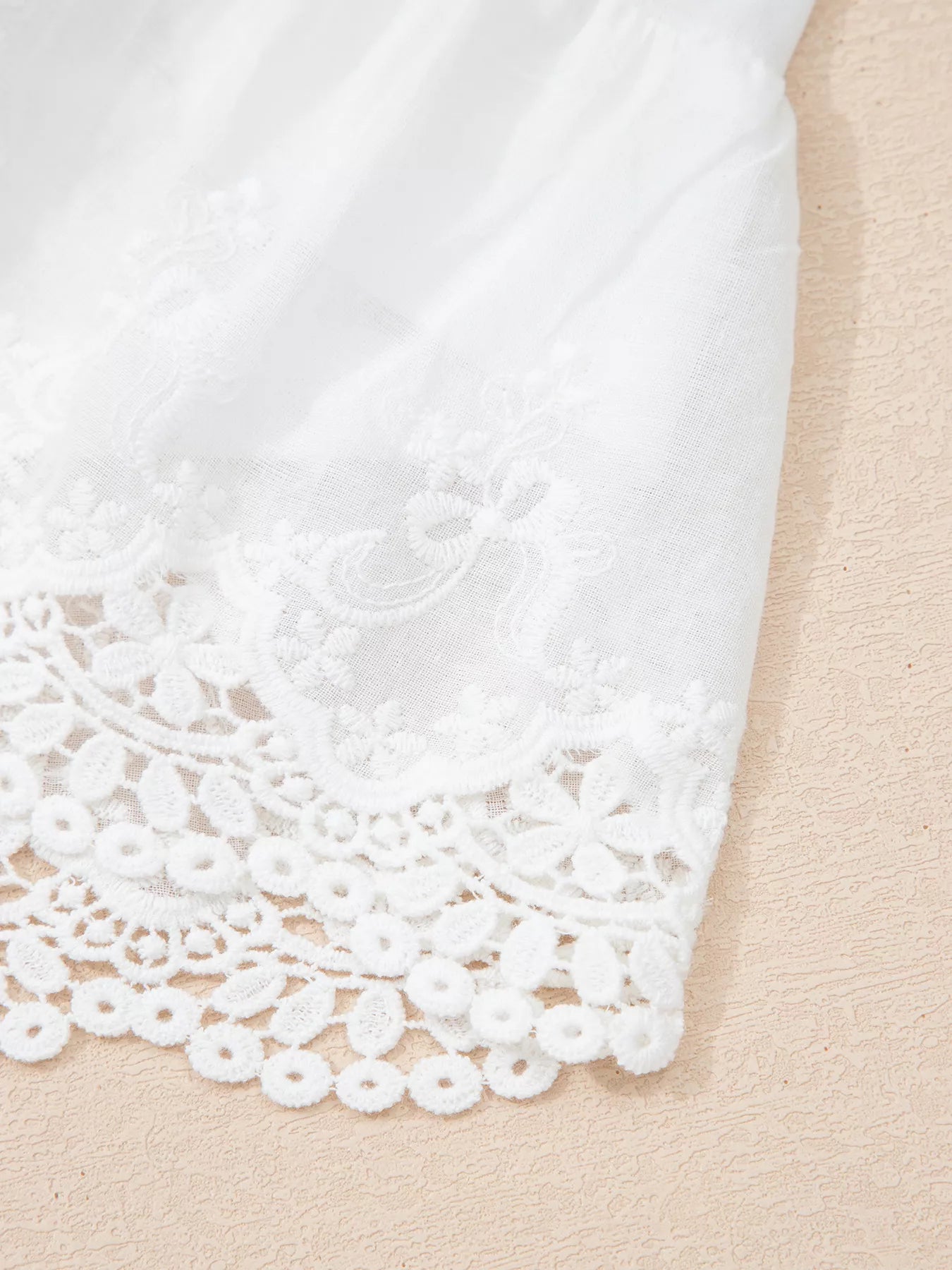 Close-up of white lace trim on a beige fabric background