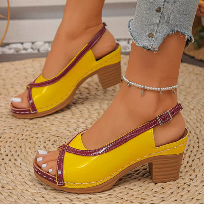 Yellow sandals with purple straps worn by a person on a textured floor.