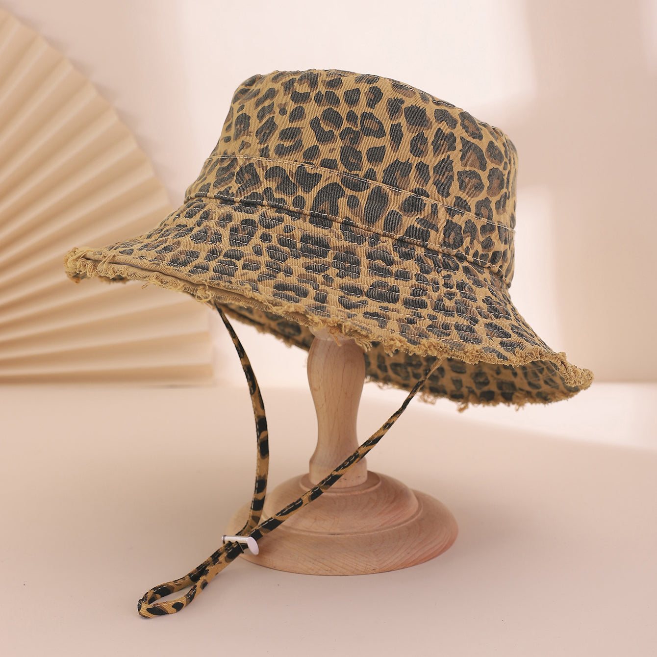 Leopard print bucket hat on a mannequin head against a beige background