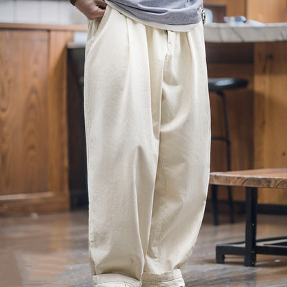 Person wearing beige wide-leg pants in a casual setting with wooden furniture.