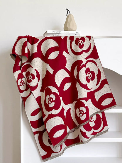 Red and white floral patterned blanket draped over a chair against a white wall.