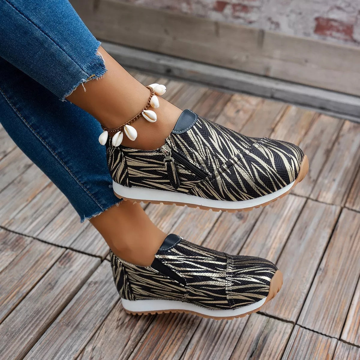 Person wearing zebra-patterned slip-on shoes on a wooden floor.