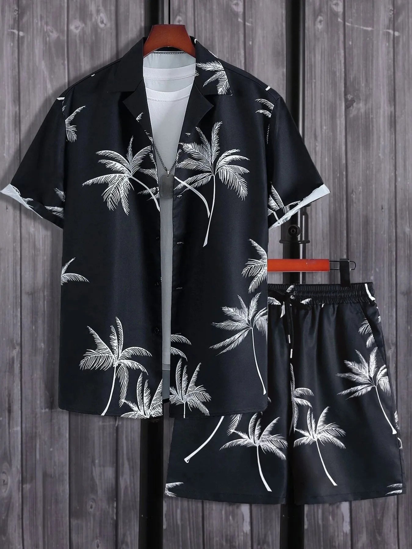 Black tropical shirt and shorts set with palm tree pattern on a wooden background