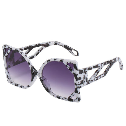 Sunglasses with black and white patterned arms and purple lenses on a white background