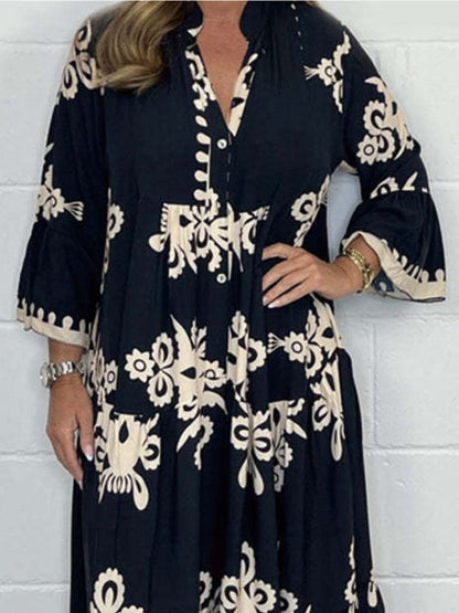 Woman wearing a black dress with white floral patterns against a white tiled wall.