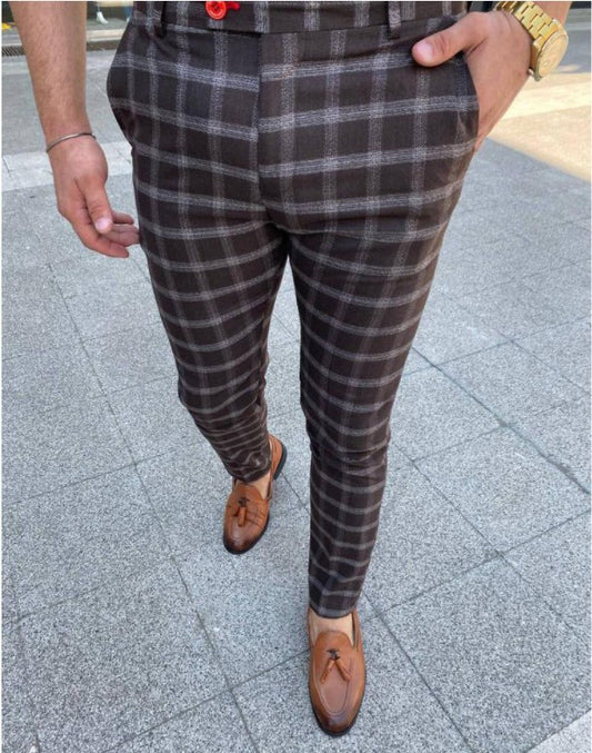 Person wearing plaid pants and brown shoes on a pavement.