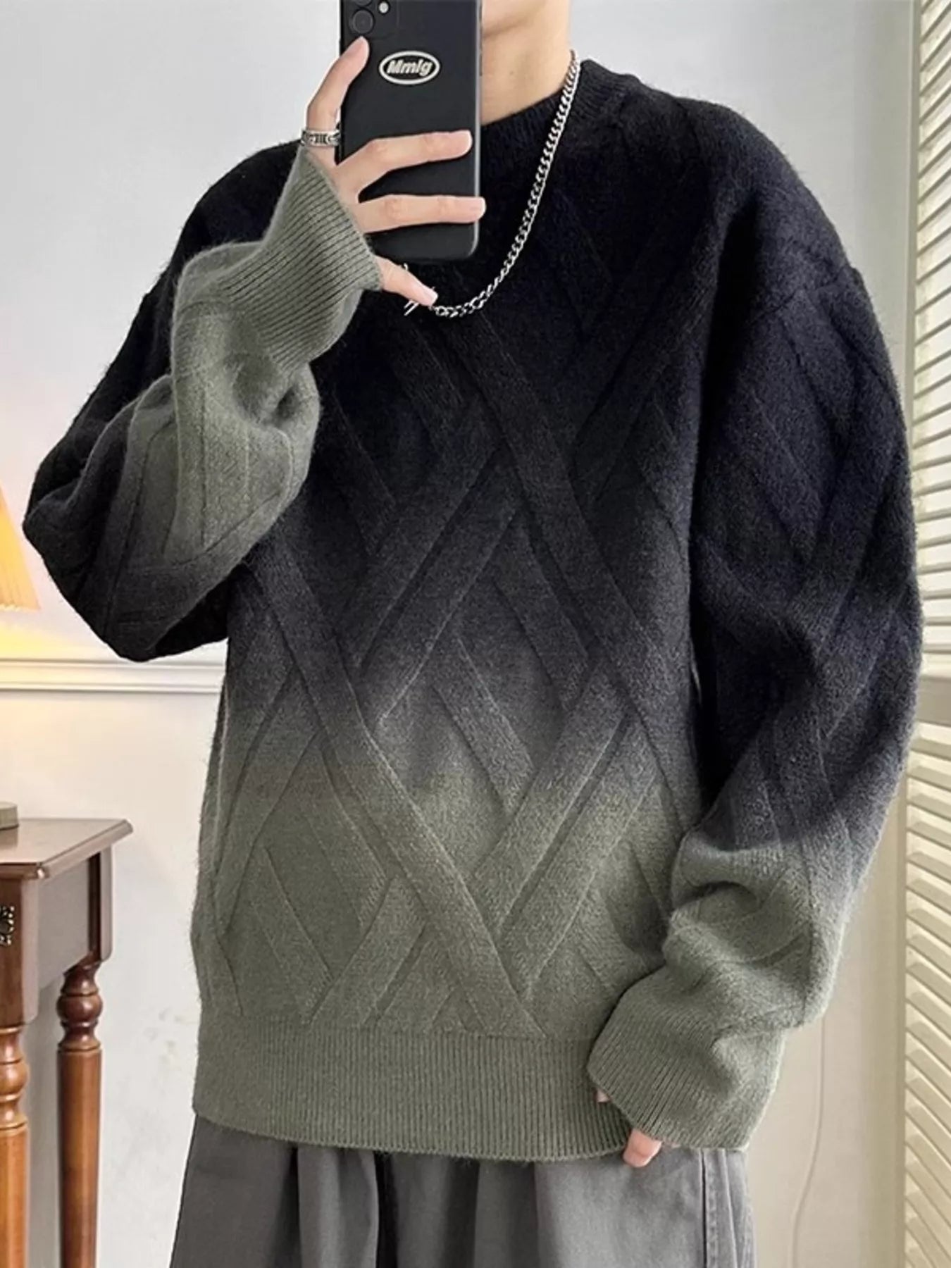 Person wearing a black and green gradient sweater taking a mirror selfie.