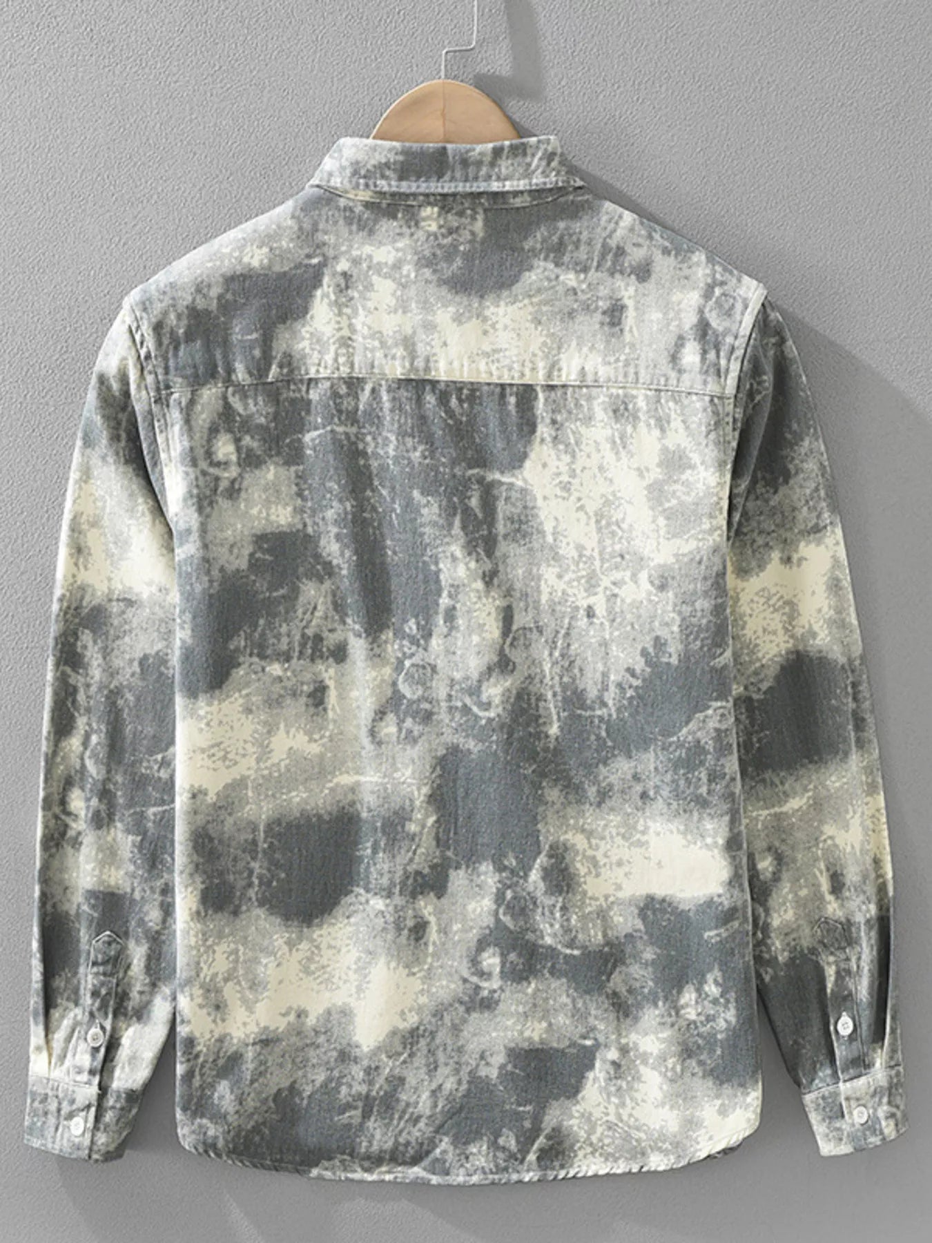 Distressed camouflage shirt on a hanger against a gray background