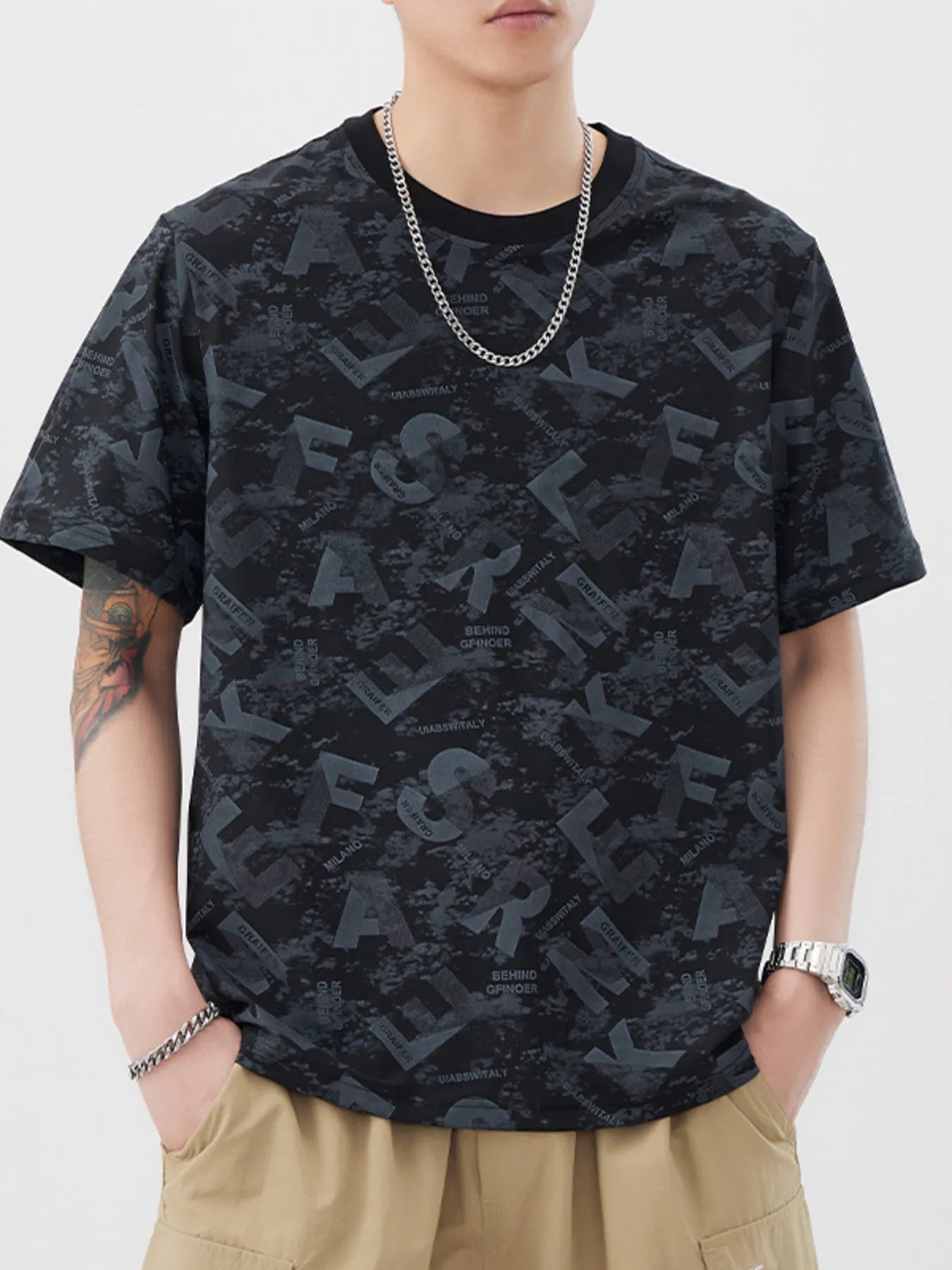 Person wearing a black patterned t-shirt and beige pants on a white background