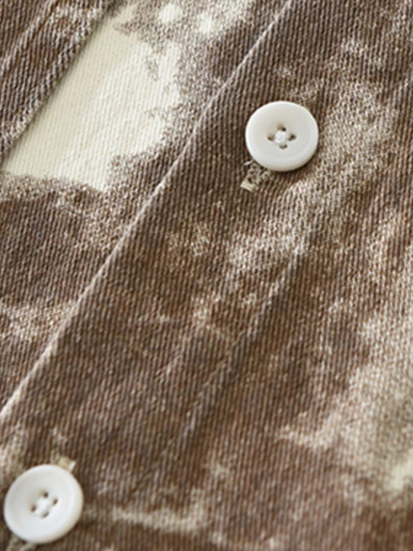 Close-up of a textured fabric with a button on a brown and beige patterned background