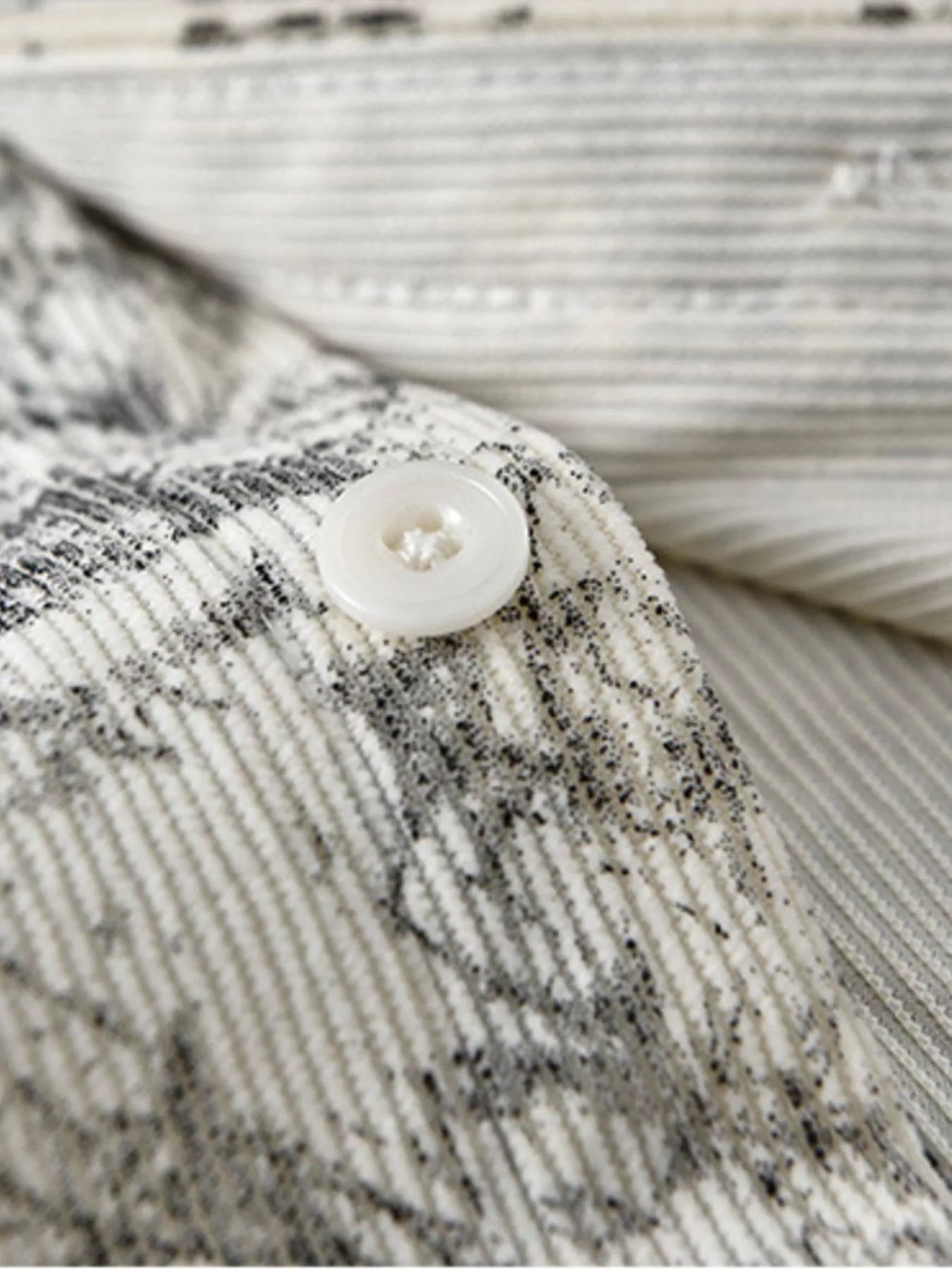 Close-up of a textured fabric with a button on a neutral background