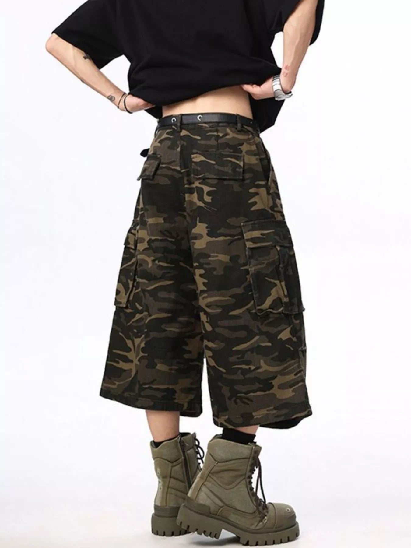 Person wearing camouflage cargo pants and green boots on a white background