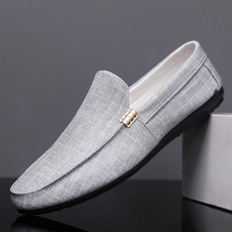 Gray loafers with a gold buckle on a dark background