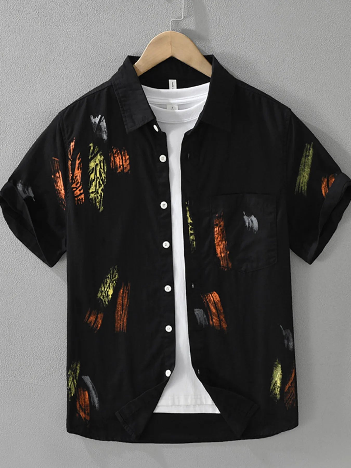 Black short-sleeve shirt with colorful patterns on a hanger against a gray background