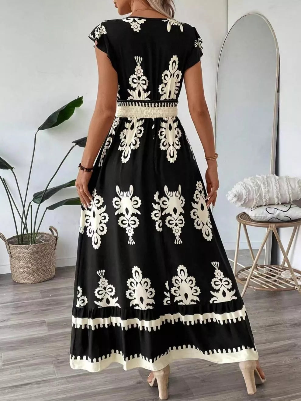 Black dress with white embroidery worn by a person in a room.