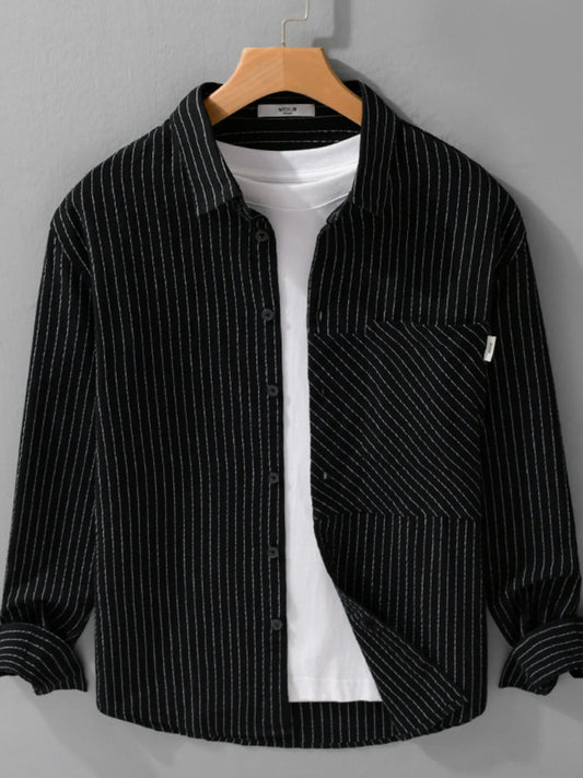 Black pinstripe shirt over a white t-shirt on a wooden hanger against a gray background