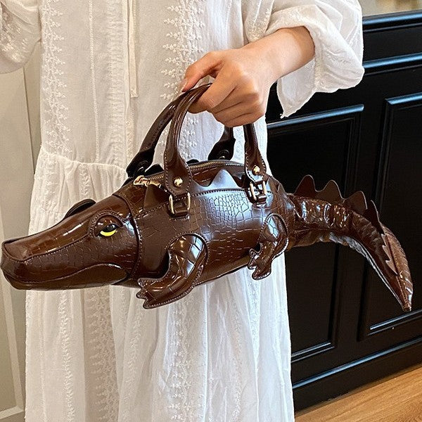 Person holding a brown alligator-shaped handbag