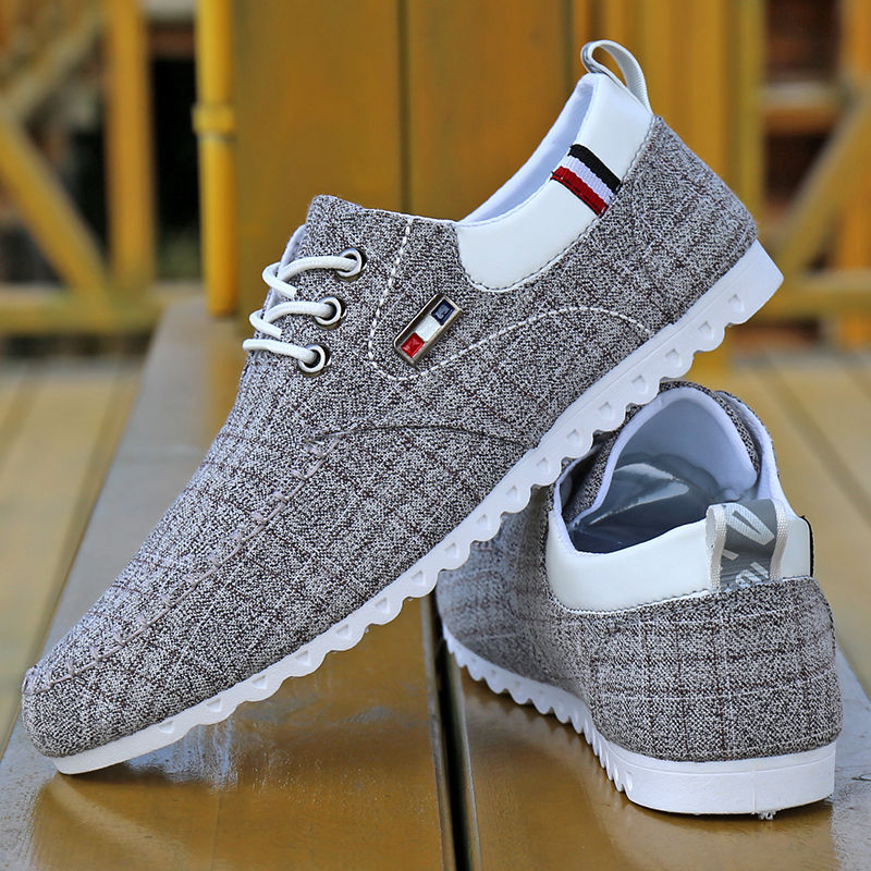 Gray textured sneakers with white soles on a reflective surface