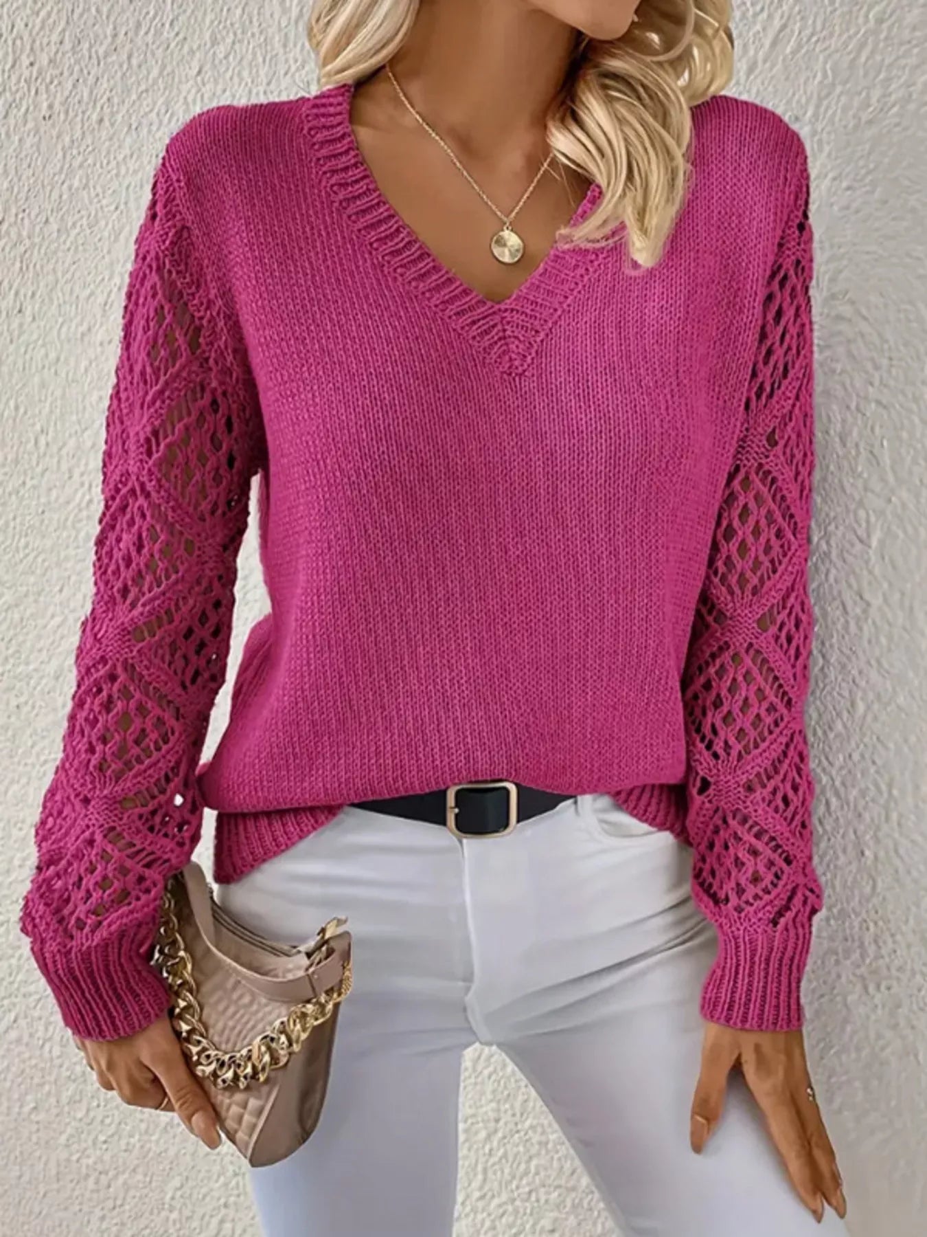 Person wearing a pink sweater with mesh sleeves against a neutral background