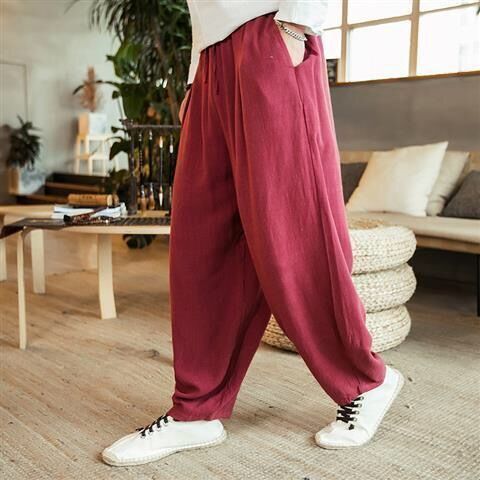 Person wearing maroon wide-leg pants and white sneakers in a living room setting.