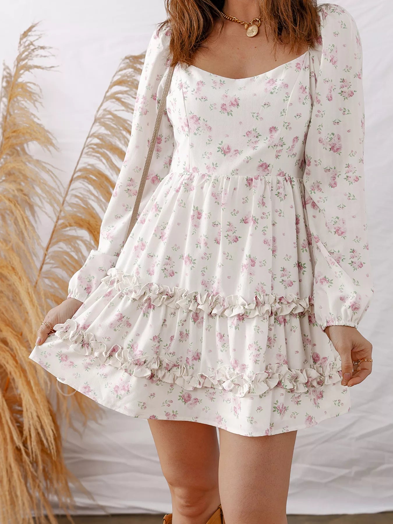 White floral dress with long sleeves worn by a person, against a neutral background.