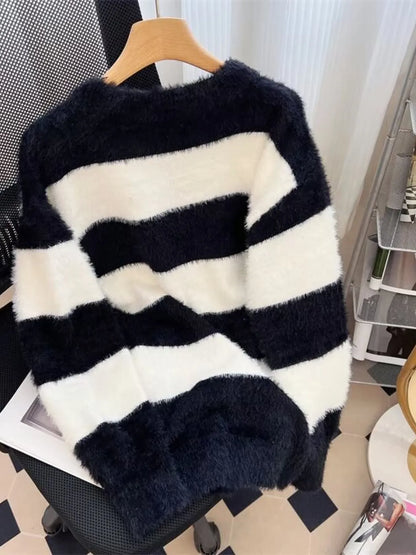 Black and white striped sweater on a hanger against a neutral background
