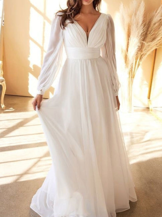 White long-sleeve gown in a softly lit room with pampas grass.