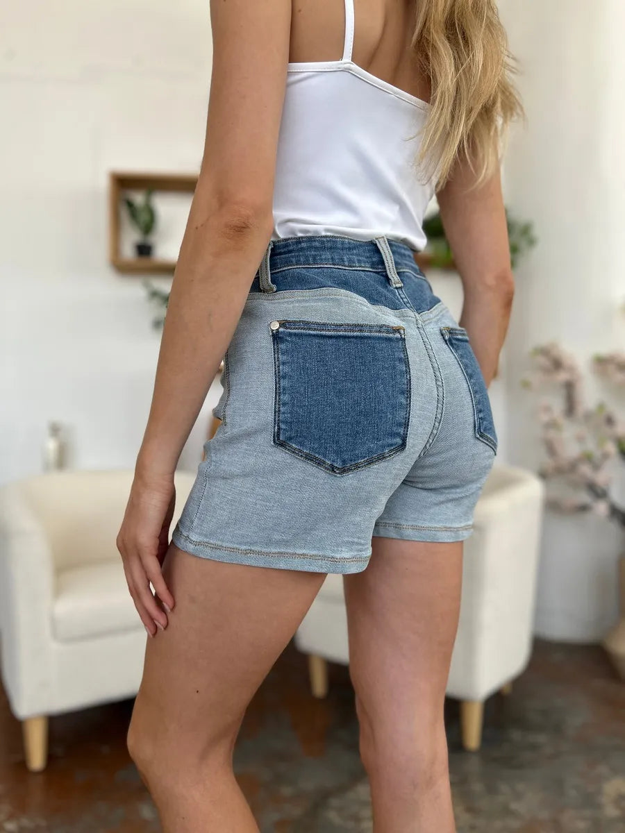 Person wearing blue denim shorts and a white top in an indoor setting