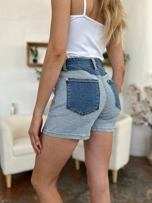 Person wearing blue denim shorts and a white top in an indoor setting